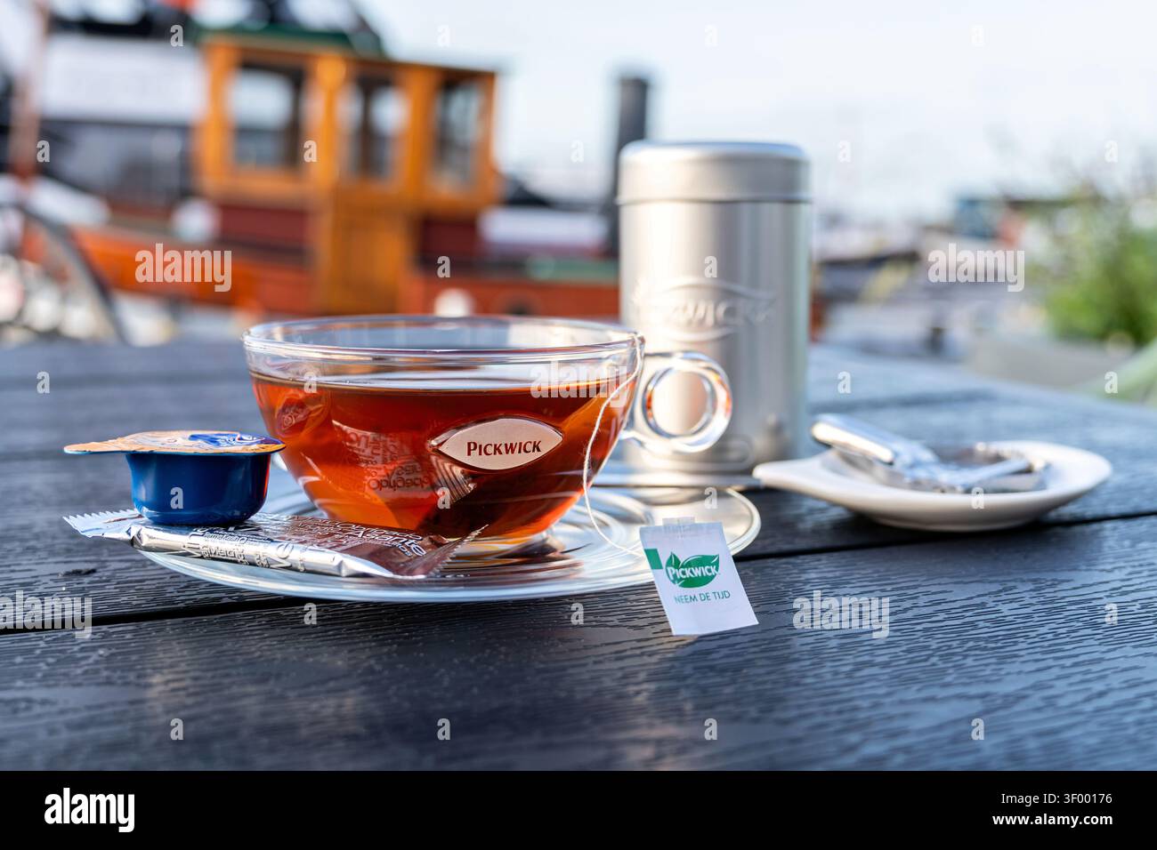 Tasse de thé noir Pickwick servi dans une tasse en verre transparent sur une soucoupe transparente Banque D'Images