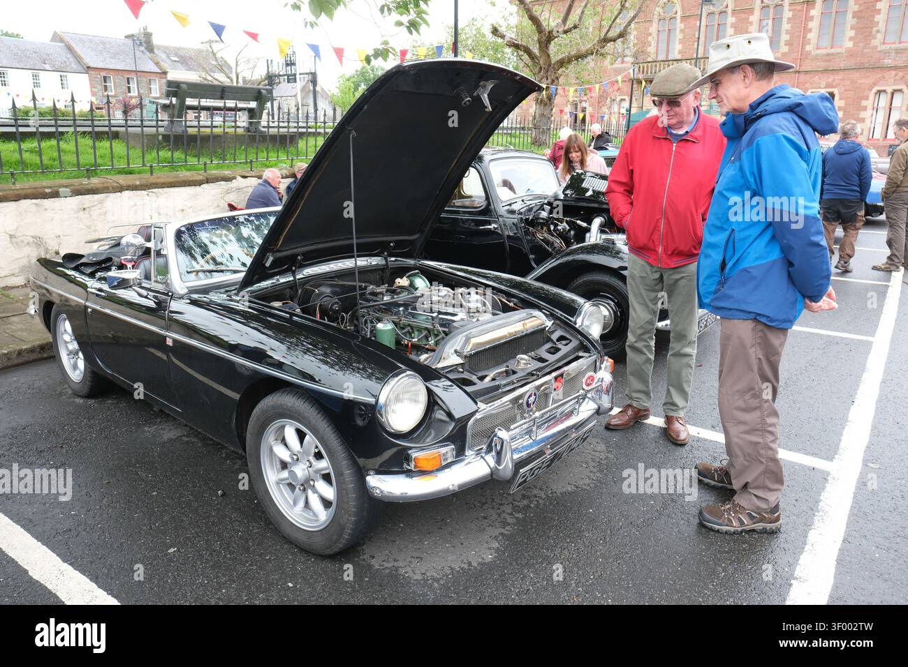 Wigtown Classic car Show - deux hommes matures admirent une voiture de sport britannique MG classique des années 1960 - photo juillet 2026 Banque D'Images