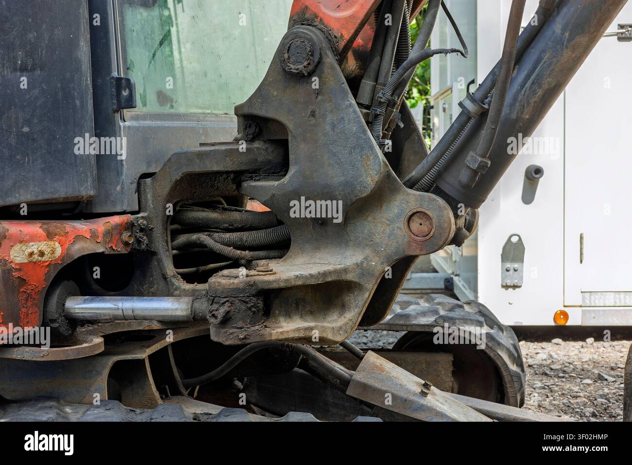 Gros plan du mécanisme de pivot hydraulique, des flexibles et du bras d'une pelle compacte pendant la restauration de ponts et les travaux de génie civil Banque D'Images