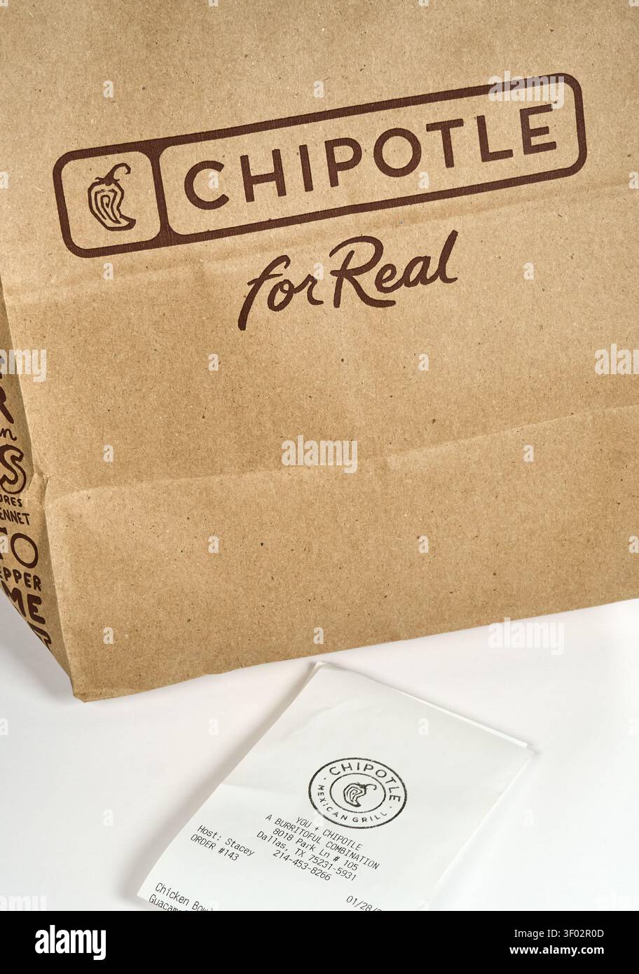 DALLAS, TX, USA - 16 FÉVRIER 2024 : un sac en papier Chipotle est montré à côté d'un reçu sur une surface blanche. Le sac affiche bien en vue le Chipotle L. Banque D'Images