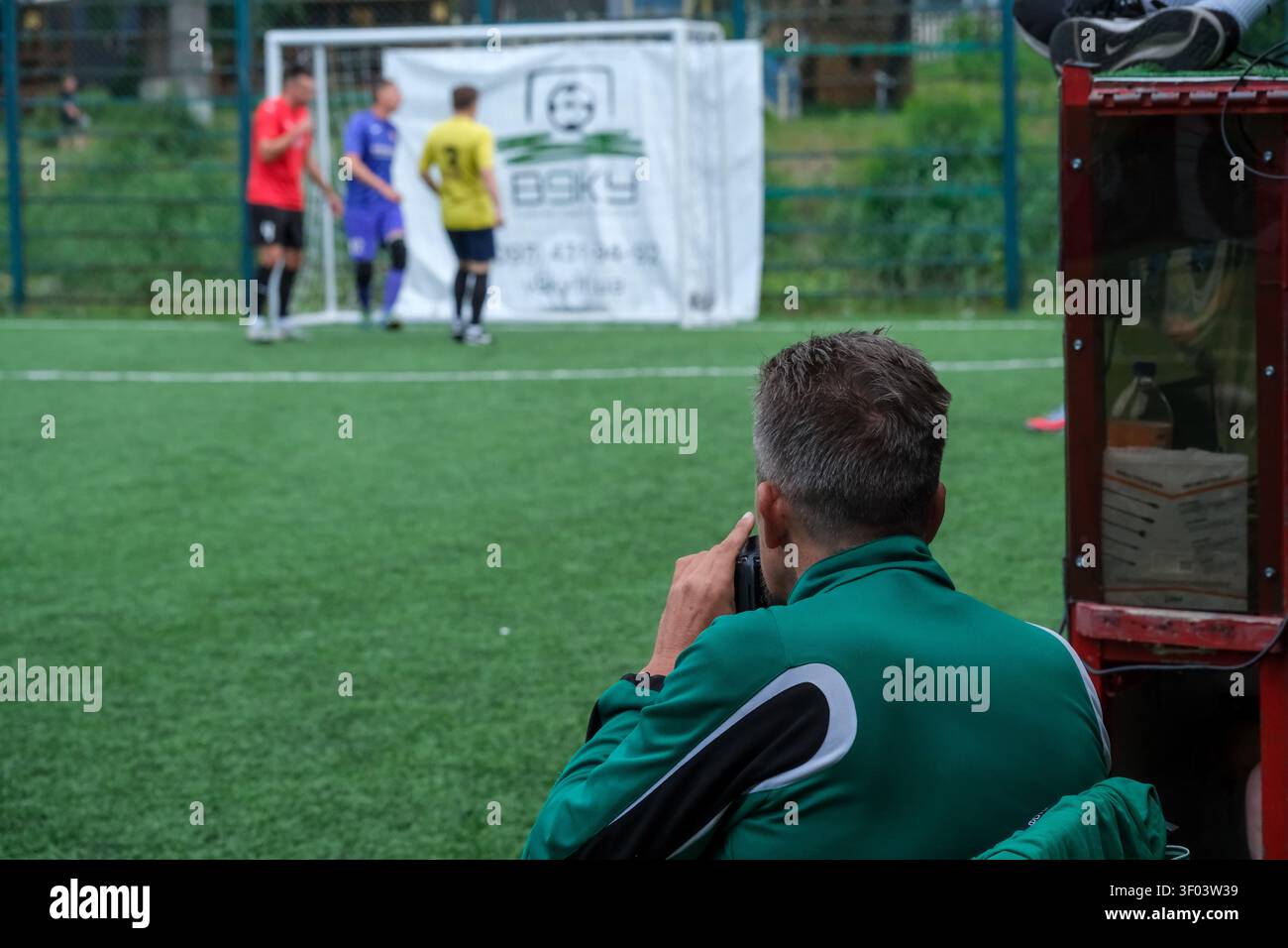KIEV, UKRAINE, 5 juillet 2026, un photographe documente un match de football amateur depuis la ligne de touche d'un terrain de football en gazon artificiel pendant une récréation Banque D'Images