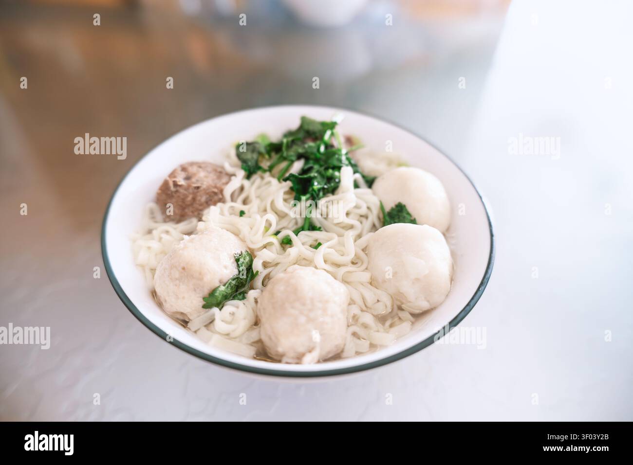 Mie Ayam indonésien avec boulettes de viande de poulet et herbes fraîches dans un bol blanc, nourriture de rue traditionnelle Banque D'Images