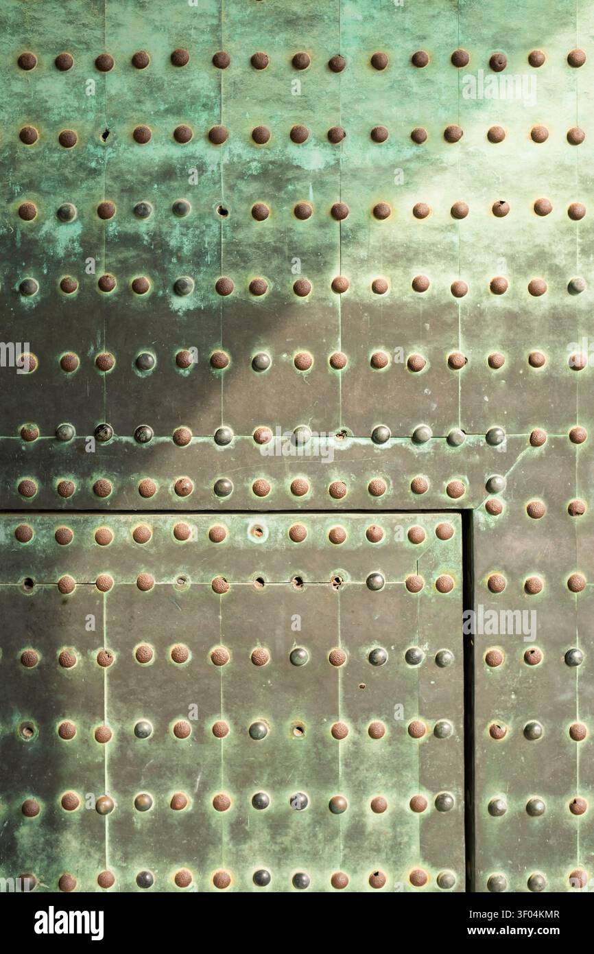 Vue détaillée en cadrage complet d'une porte métallique verte historique parsemée de rangées de rivets ronds en laiton, Kyoto, Japon Banque D'Images