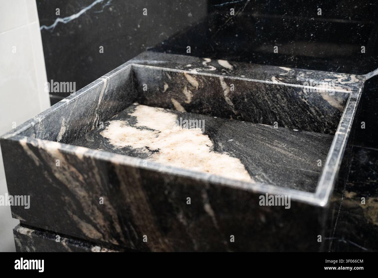 Lavabo de salle de bain de luxe en marbre noir avec des veines élégantes dans les toilettes commerciales. Hygiène haut de gamme et design d'intérieur sophistiqué. Banque D'Images