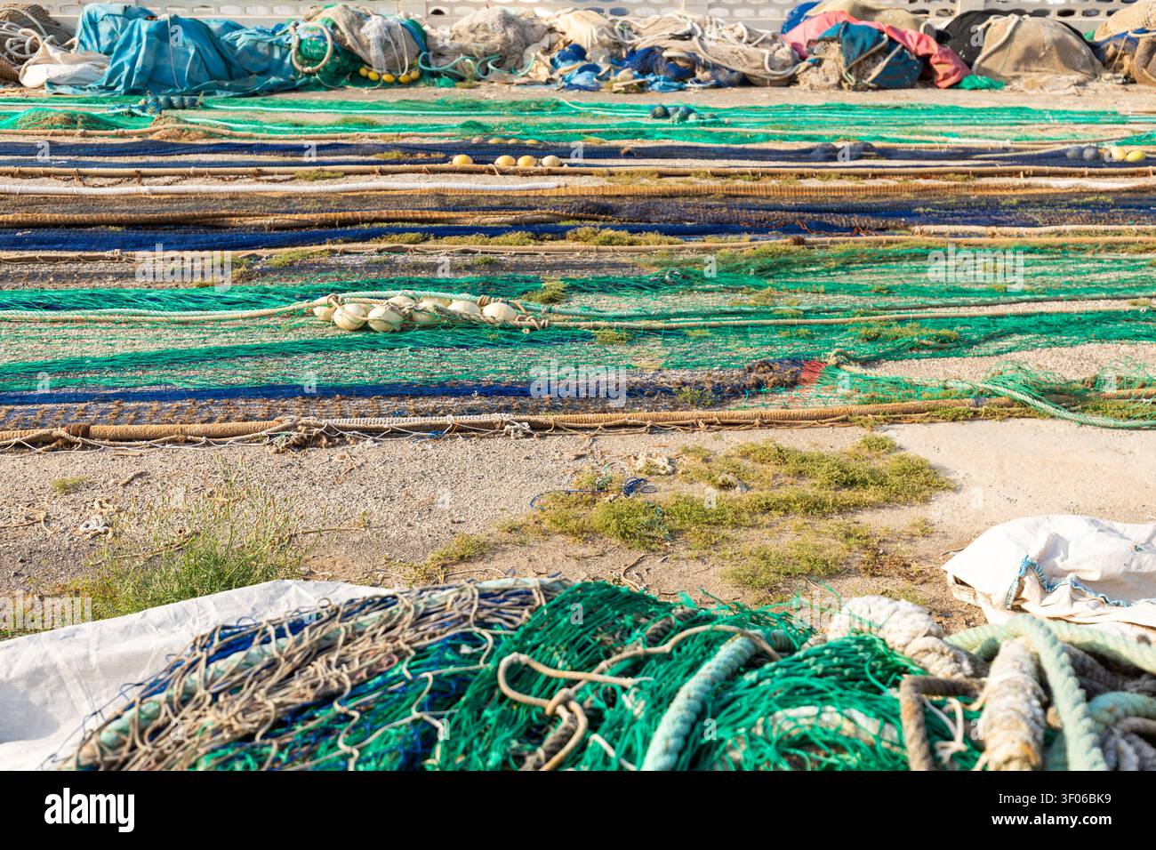 Gros plan de filets de pêche colorés, de cordes et de flotteurs disposés pour sécher sur un quai portuaire en activité à Calpe, en Espagne, montrant la texture maritime, les engins et la côte Banque D'Images