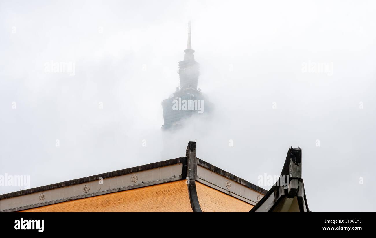 Le toit orné du National Sun Yat-sen Memorial Hall se dresse bien en évidence avec la flèche emblématique de Taipei 101 enveloppée de brouillard en arrière-plan Banque D'Images