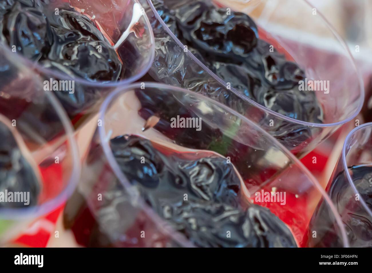 Grossissement d'un garnissage de dessert aux baies sombres dans des coupelles en plastique individuelles, créant un détail de buffet de catering festif avec une texture fruitée brillante, une mise au point douce et Banque D'Images
