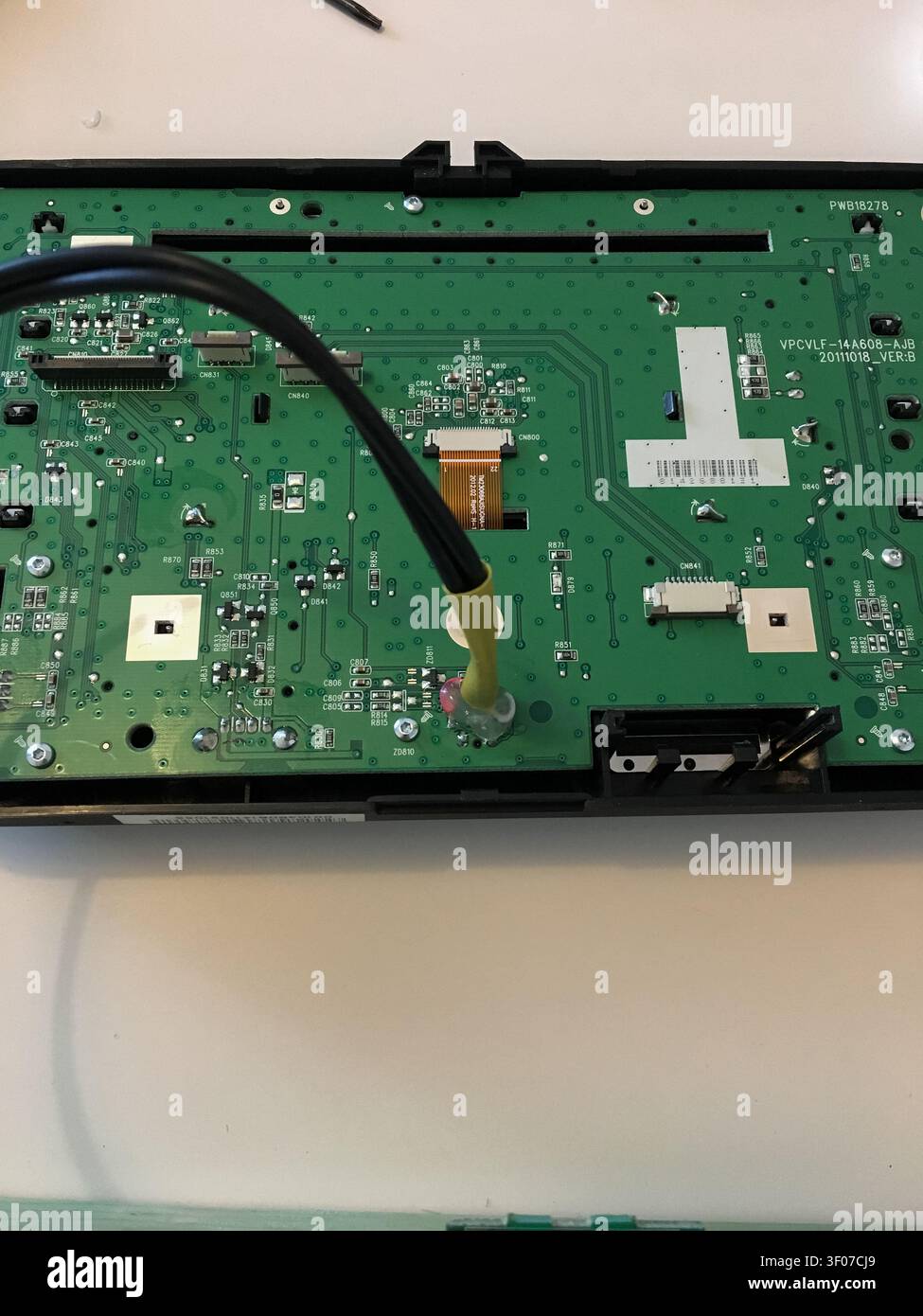 Gros plan d'un carte mère de télévision avec un câble coaxial noir et un connecteur ruban. Banque D'Images