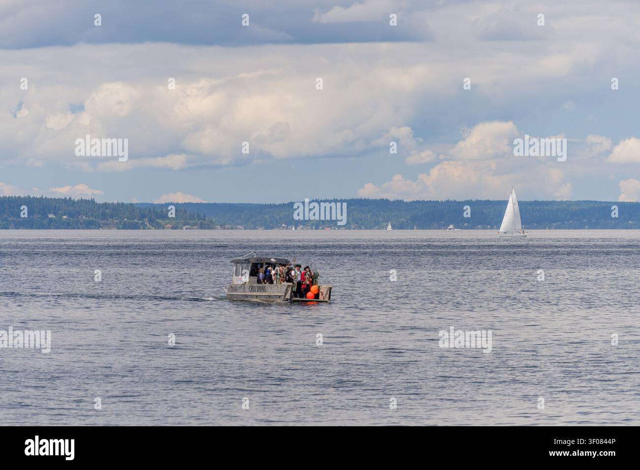 État de Washington, États-Unis, 27 JUI 2026 - Un petit bateau de tourisme transportant des passagers se déplace sur l'eau tandis qu'un voilier blanc glisse à proximité Banque D'Images