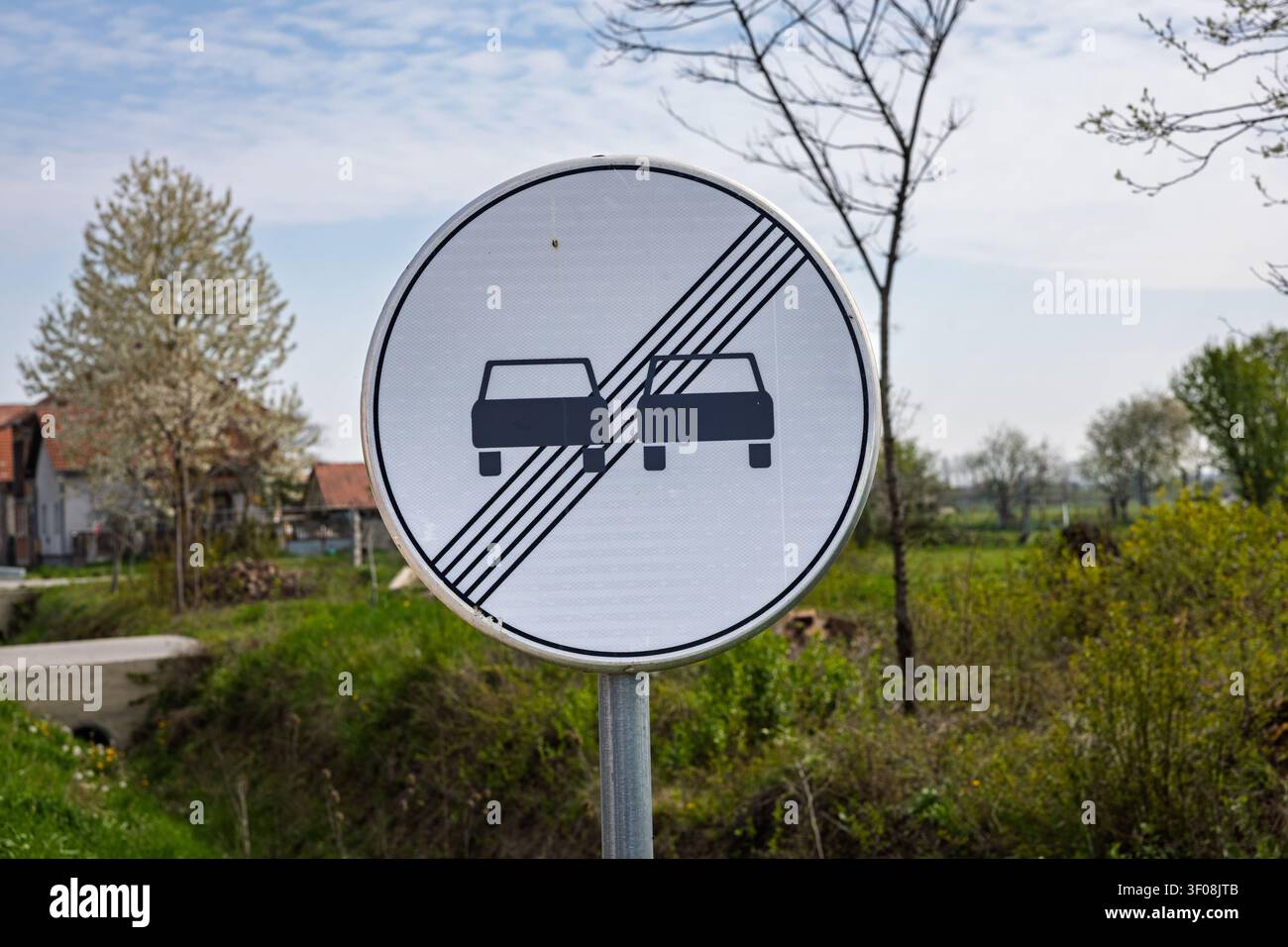 Le panneau d'interdiction de dépassement sur une route rurale indique la fin d'une zone de dépassement et impose la sécurité routière. Panneau métallique circulaire avec symboles de voitures debout Banque D'Images