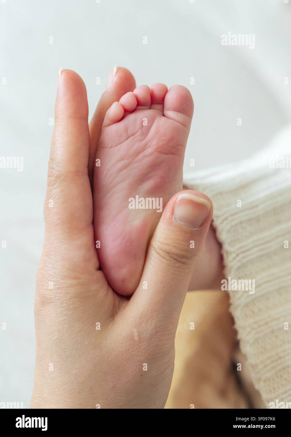 Close-up des pieds d'un nouveau-né dans les mains de sa mère. Concept de soins, famille, parentalité, tendresse, protection, petite enfance Banque D'Images