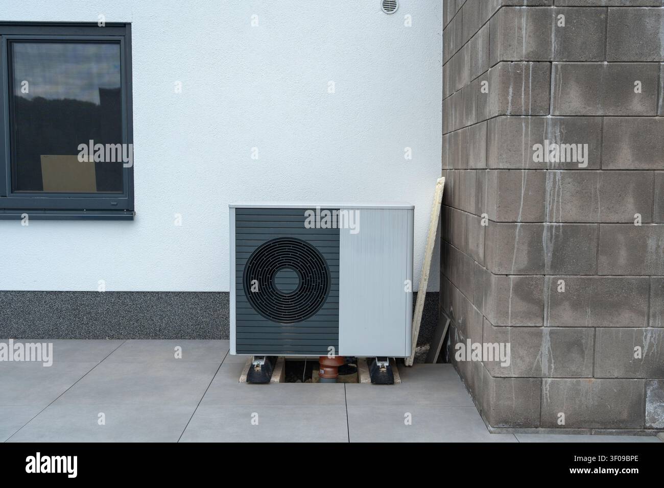 une unité de climatisation stationnaire installée du côté extérieur d'un bâtiment résidentiel, mettant en valeur un design neutre et fonctionnel avec du gris et Banque D'Images