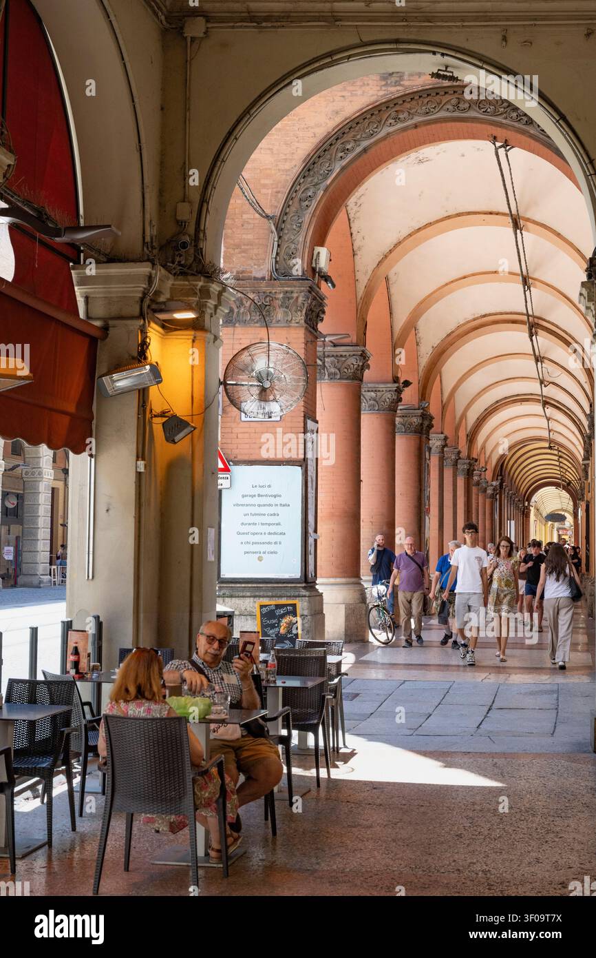 Piétons et cafés à l'ombre des portiques sur la via Dell' Indipendenza dans le centre de Bologne, Emilie-Romagne, Italie du Nord. Banque D'Images