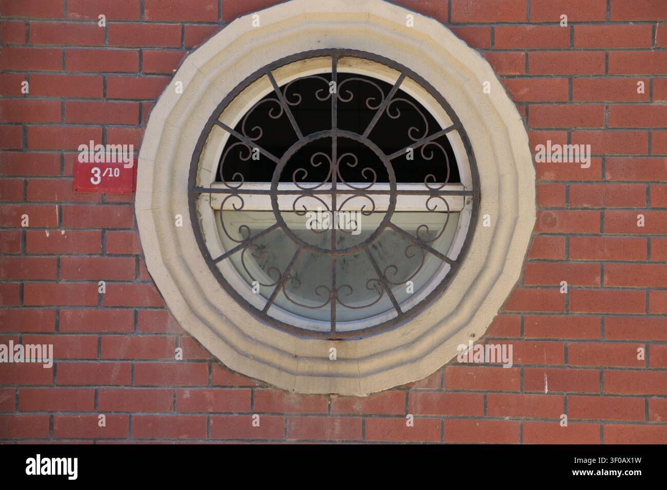 Fenêtre circulaire et numéro de maison sur un mur de briques Banque D'Images