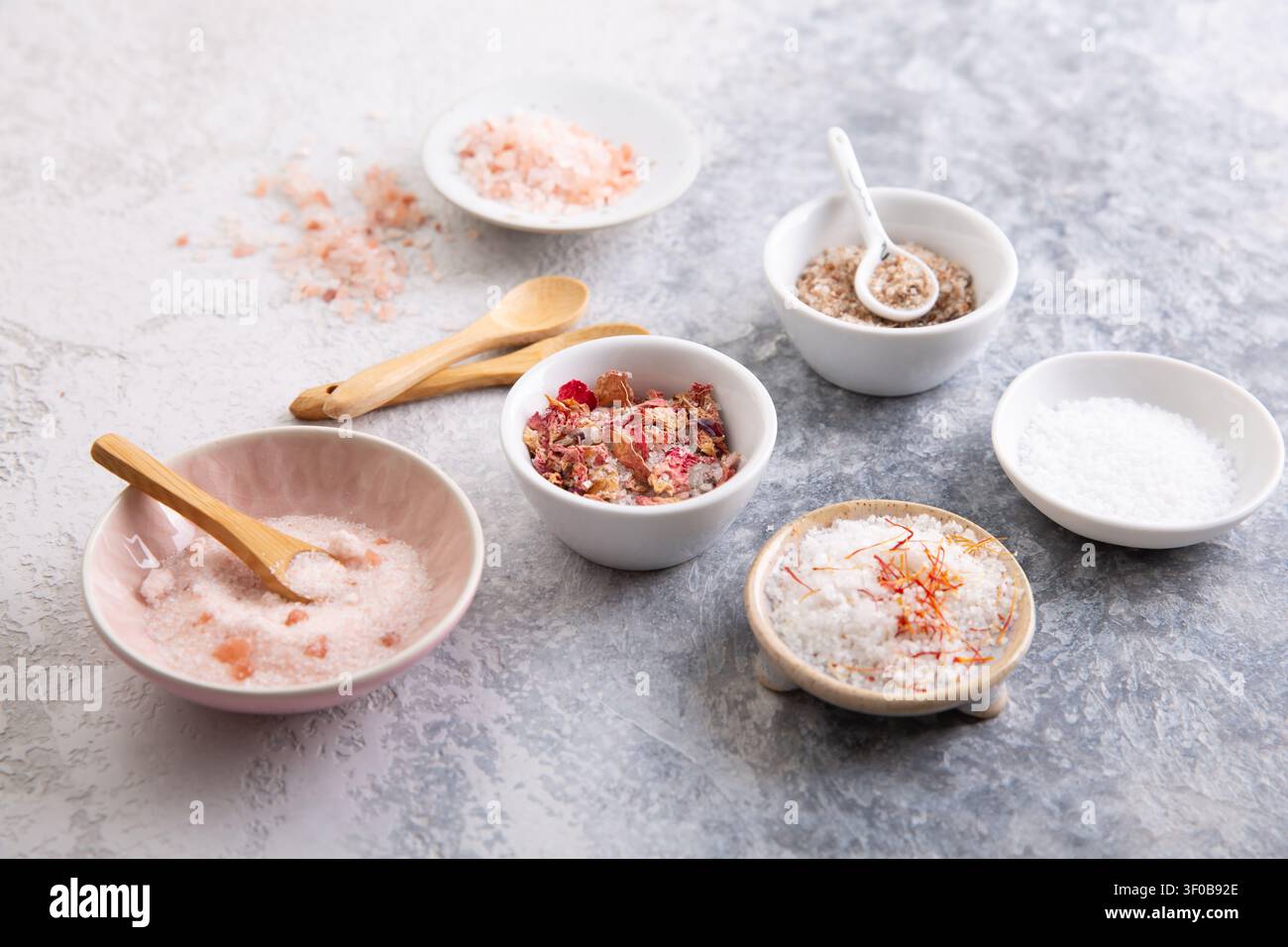 Assortiment de sels gastronomiques dans de petits bols, y compris l'Himalaya et les pétales de rose infusés Banque D'Images