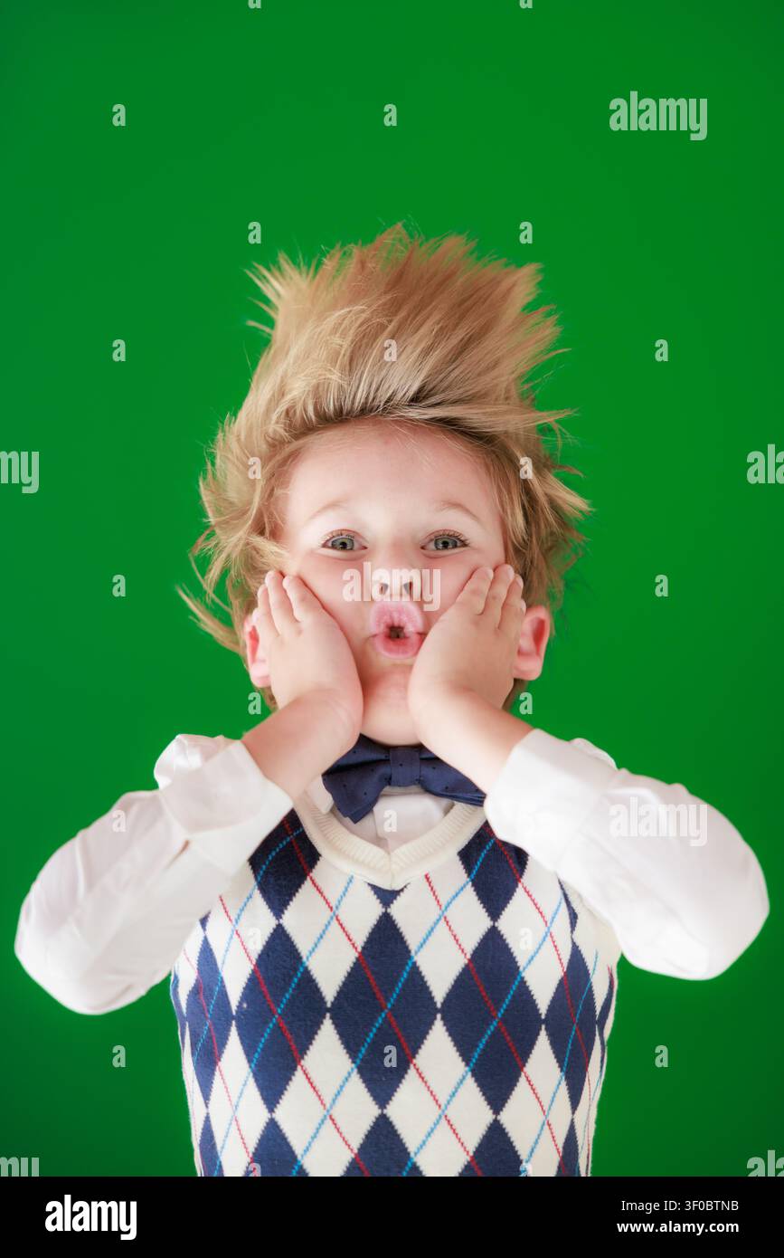 Enfant surpris en classe. Enfant drôle devant un fond de tableau vert. Concept de retour à l'école et d'éducation Banque D'Images