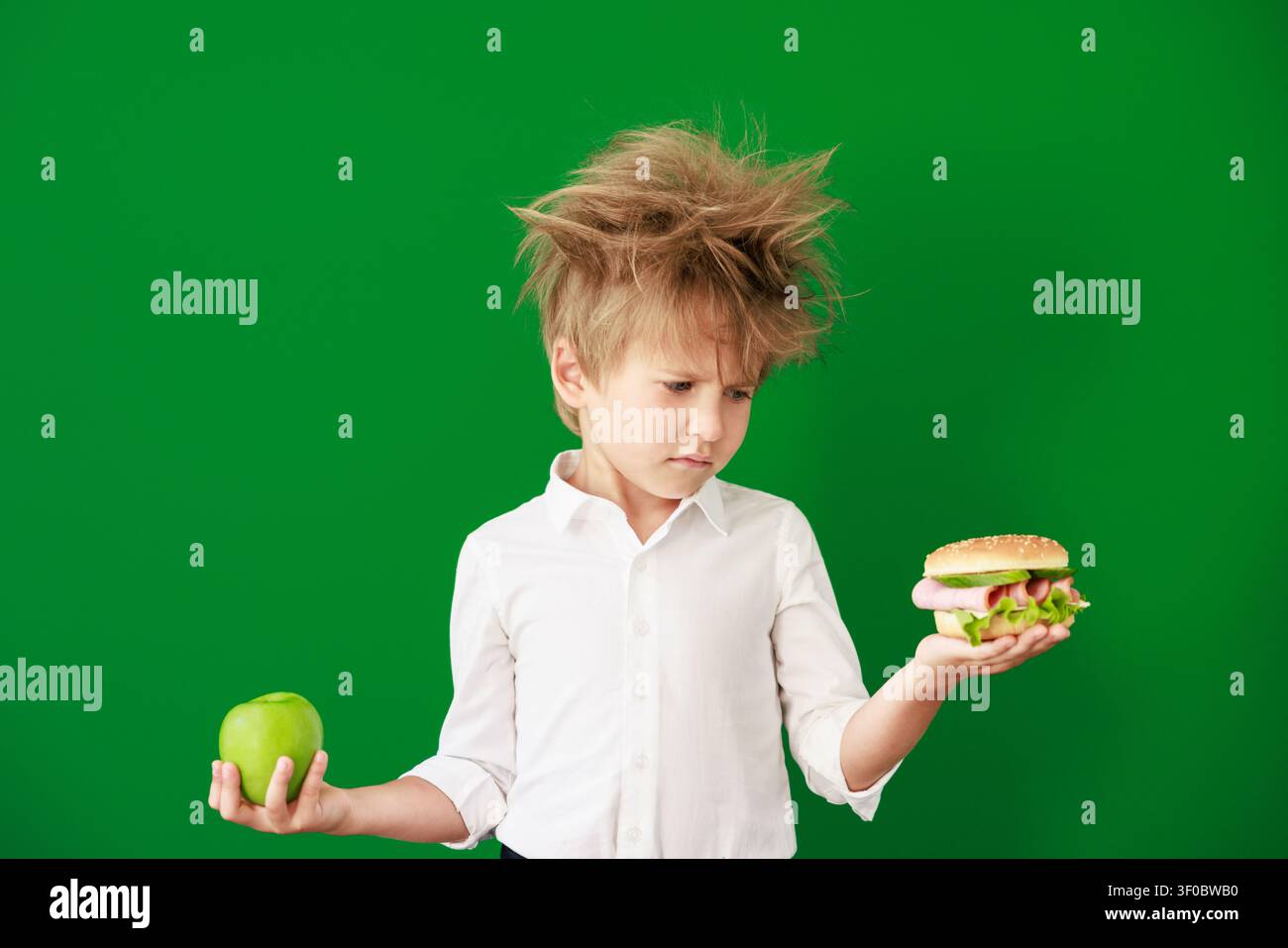Enfant surpris en classe. Enfant drôle devant un fond de tableau vert. Concept de retour à l'école et d'éducation Banque D'Images