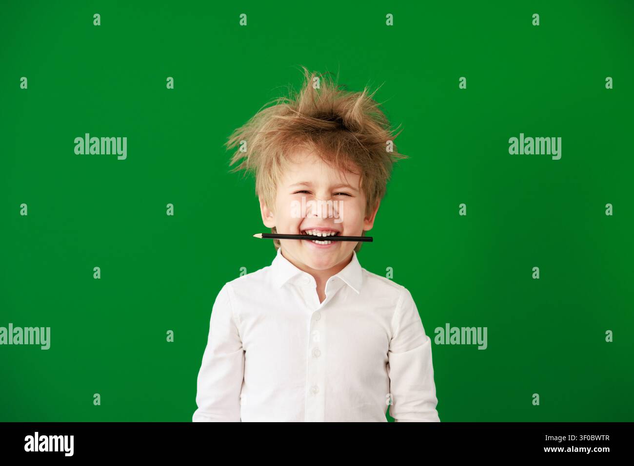 Enfant heureux en classe. Enfant drôle devant un fond de tableau vert. Concept de retour à l'école et d'éducation Banque D'Images