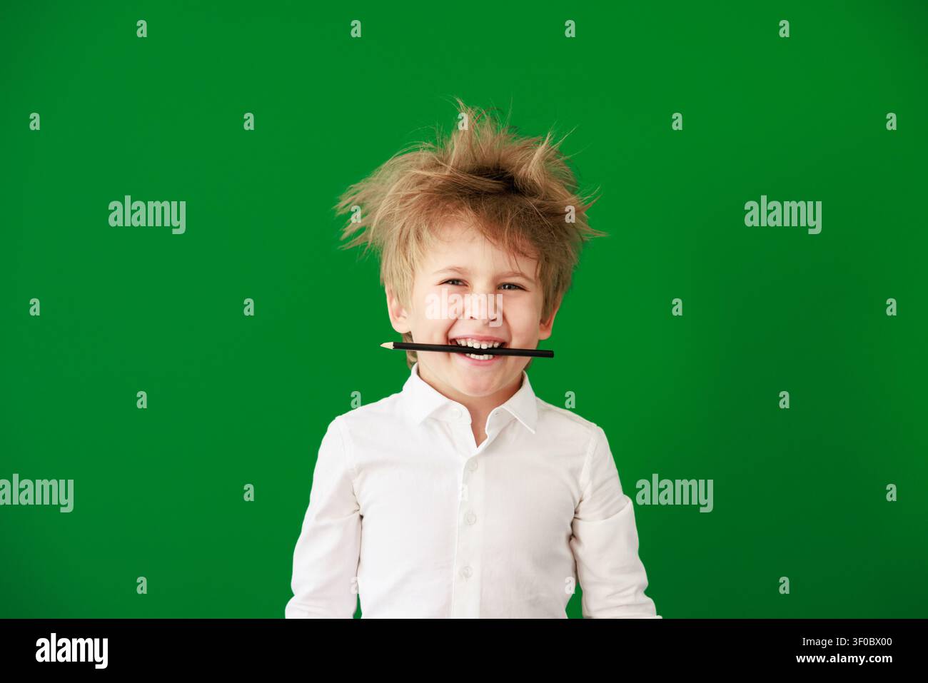 Enfant heureux en classe. Enfant drôle devant un fond de tableau vert. Concept de retour à l'école et d'éducation Banque D'Images