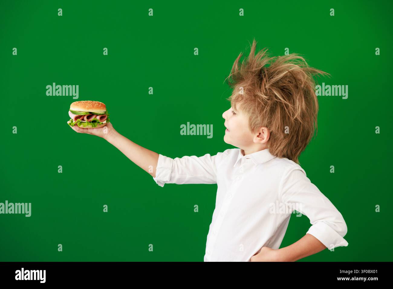 Enfant surpris en classe. Enfant drôle devant un fond de tableau vert. Concept de retour à l'école et d'éducation Banque D'Images
