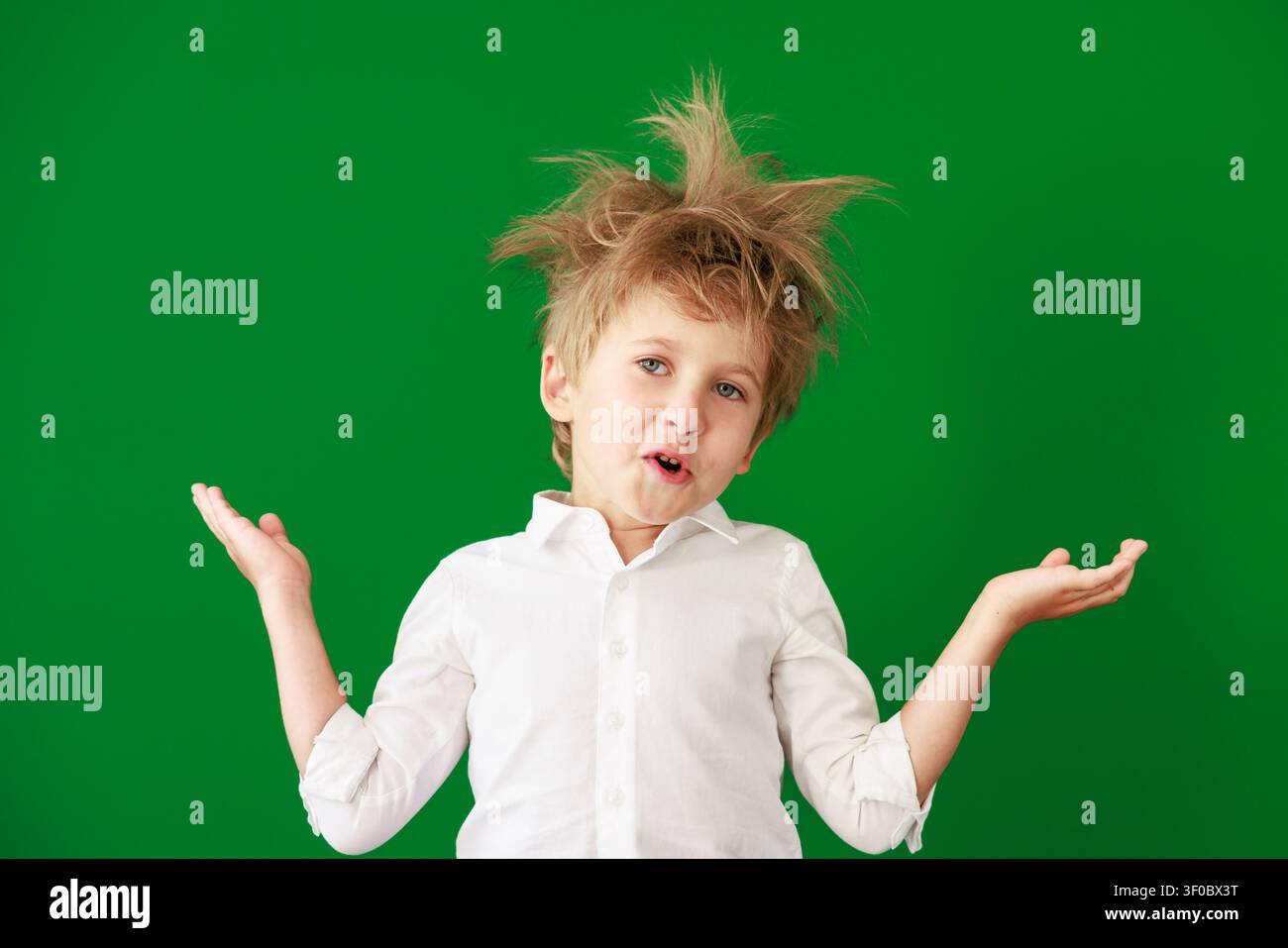 Enfant surpris en classe. Enfant drôle devant un fond de tableau vert. Concept de retour à l'école et d'éducation Banque D'Images