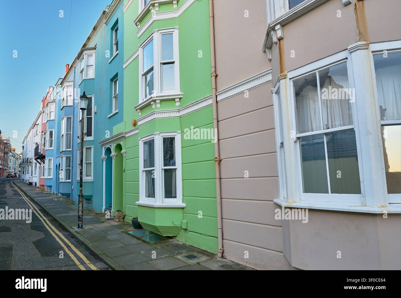 Maisons en terrasse colorées sur une rue résidentielle ensoleillée d'une ville côtière. Banque D'Images