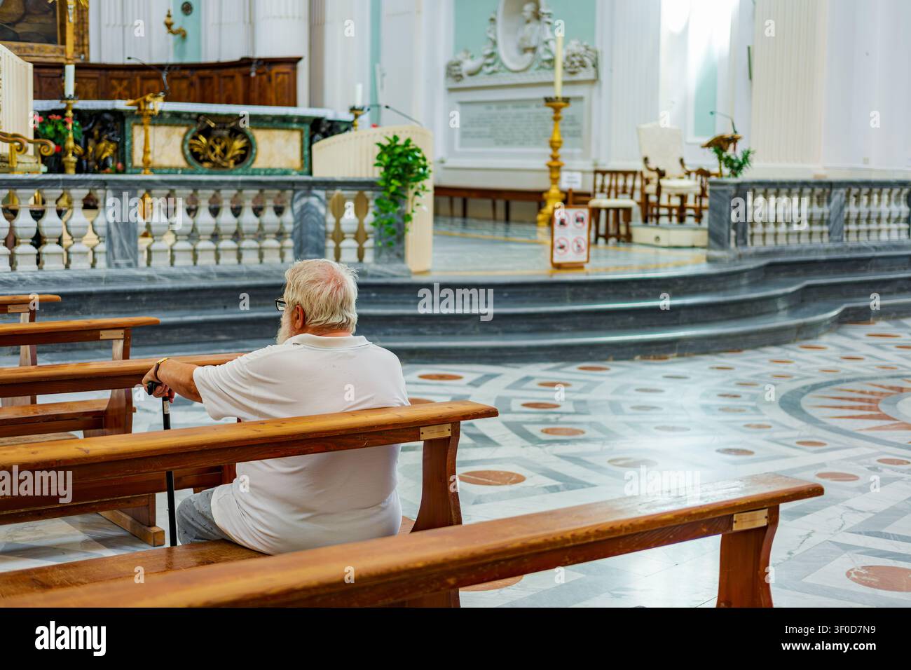 Ancien homme assis à l'intérieur de l'église Duomo di Urbino Banque D'Images