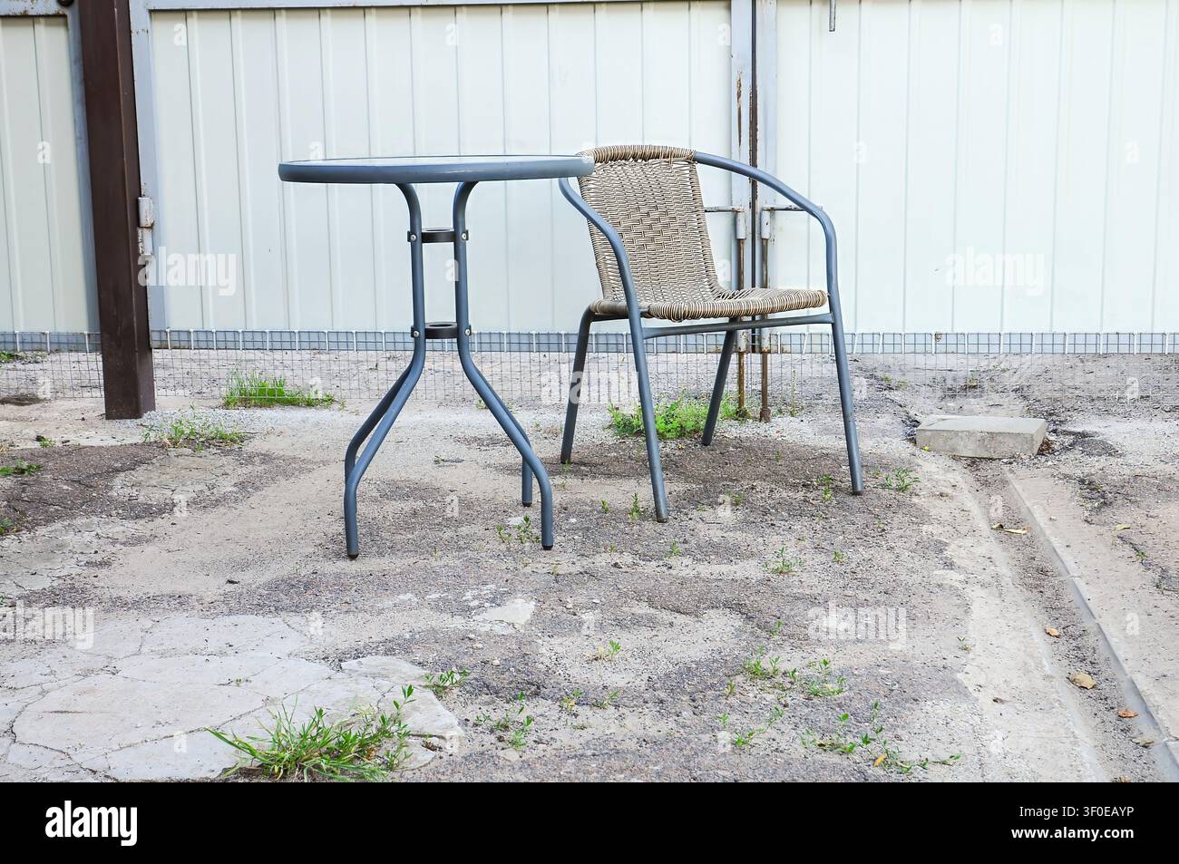 Ensemble table et chaise d'extérieur sur une terrasse en gravier avec un fond mural blanc Banque D'Images