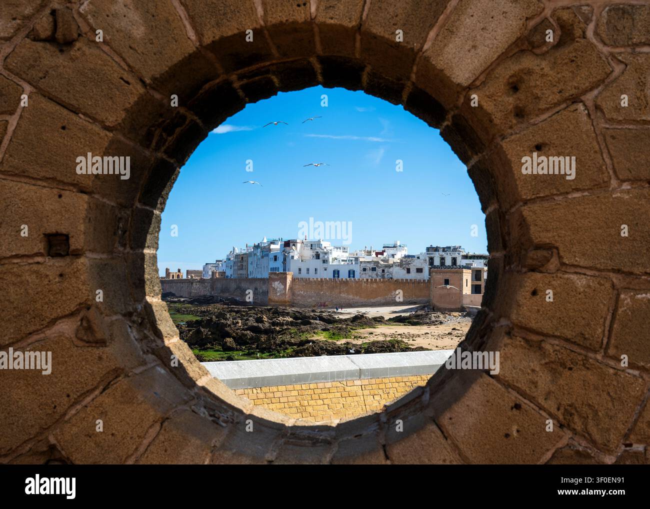 Vue des anciens remparts et de la médina à travers une ouverture circulaire dans le mur de Skala du Port dans la ville côtière d'Essaouira au Maroc, en Afrique du Nord Banque D'Images