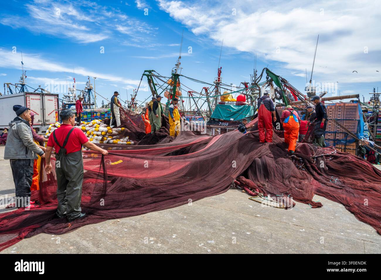 Pliage et chargement de filets de pêche dans le port animé d'Essaouira au Maroc, en Afrique du Nord Banque D'Images