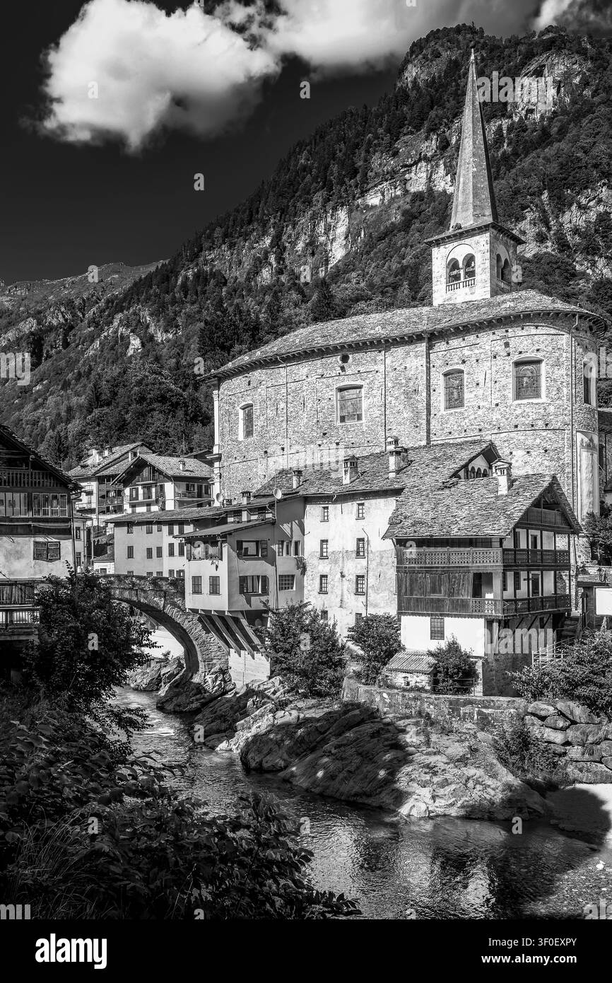 Une vue en noir et blanc de l'église historique en pierre et des maisons alpines traditionnelles de Campertogno, Italie Banque D'Images
