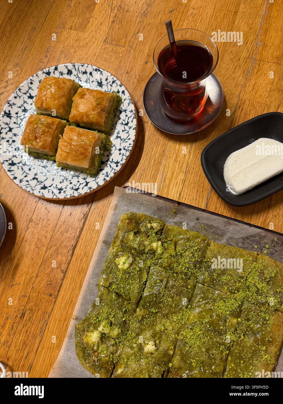 Le katmer turc traditionnel, le baklava aux pistaches, le dondurma et le thé noir sont servis sur une table en bois. Cuisine turque, dessert, gastronomie, culture alimentaire Banque D'Images
