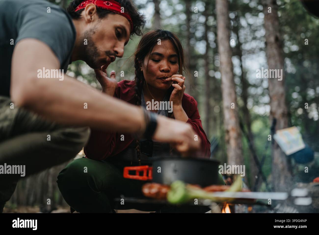 Couple cuisinant sur un feu de camp en camping dans une forêt en plein air ensemble Banque D'Images