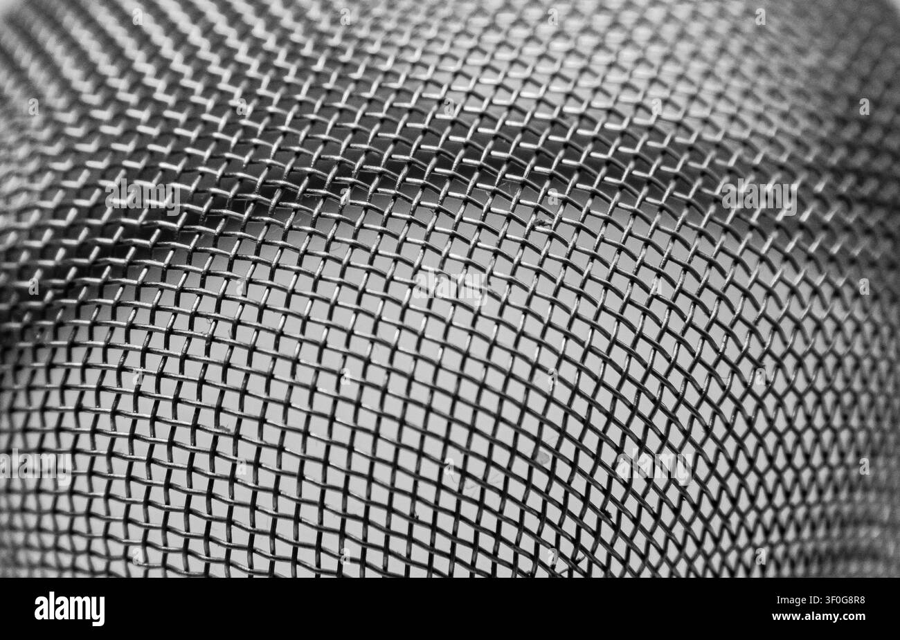 Grille en treillis métallique incurvée montrant la texture de fil tissé en détails abstraits Banque D'Images