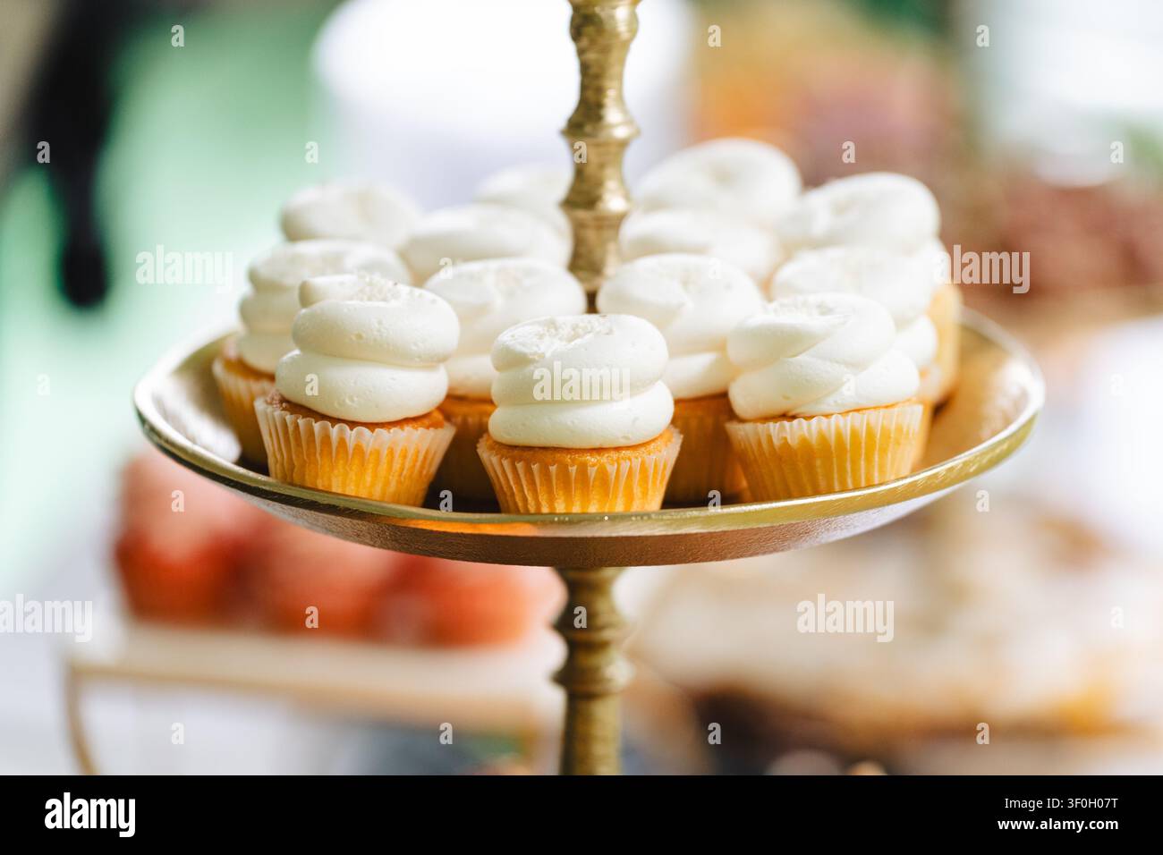 Mini cupcakes à la vanille avec glaçage au beurre blanc sur un support doré Banque D'Images