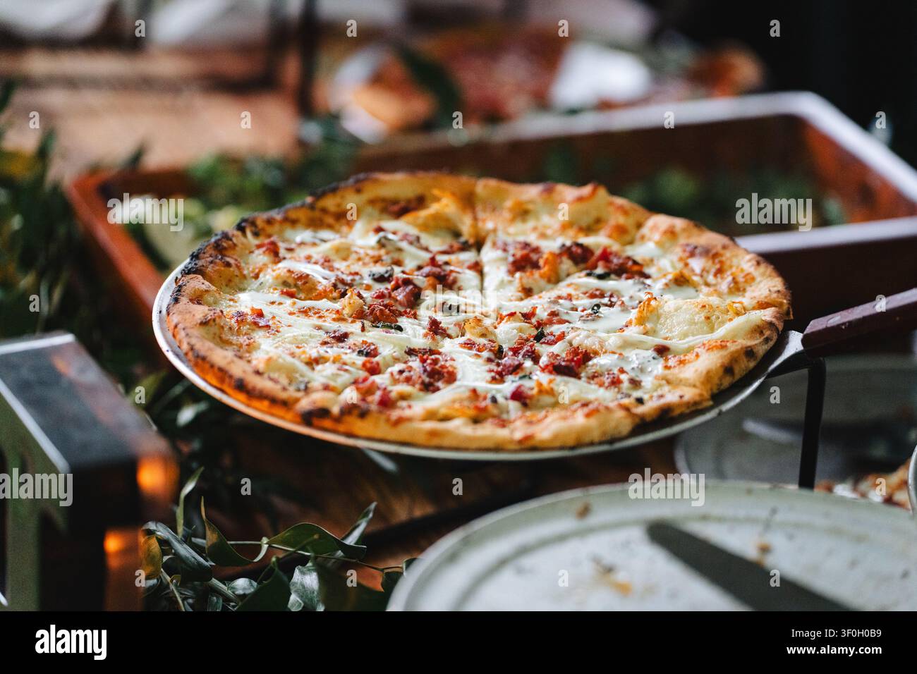 Pizza blanche gastronomique fraîche avec bacon sur un plateau lors d'un événement de catering Banque D'Images