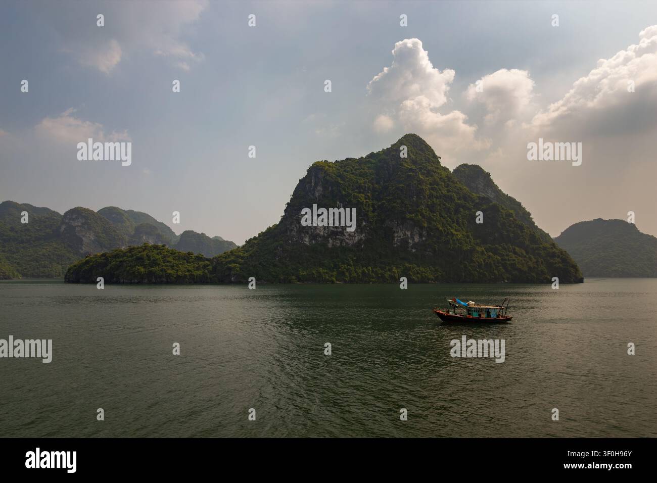 Grandes îles karstiques dans la baie d'Halong, Vietnam, avec un bateau jonque traditionnel Banque D'Images