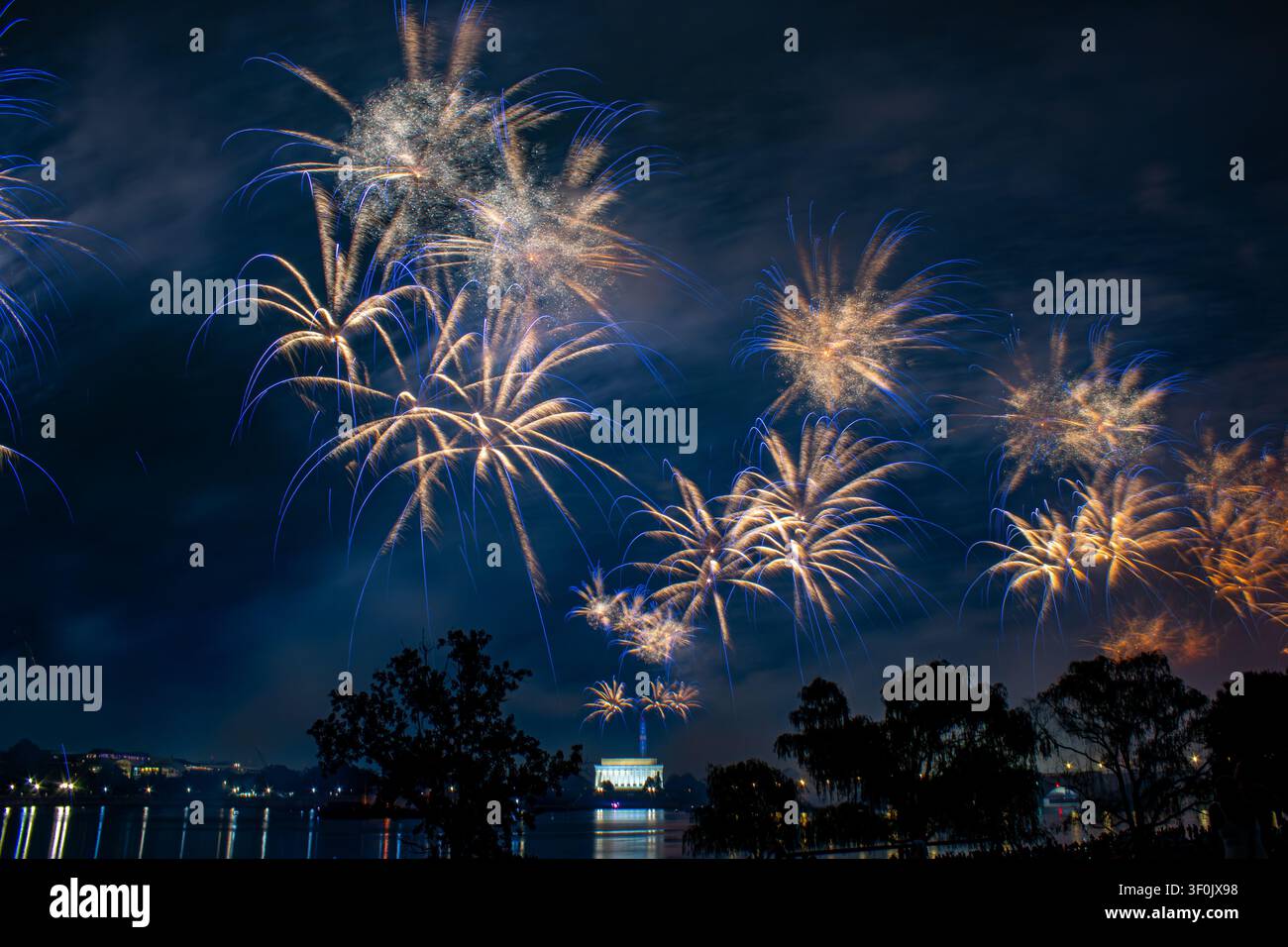 Washington, DC, États-Unis – 4 juillet 2026 : Des feux d’artifice dorés avec des traînées de comètes bleues éclatent au-dessus du fleuve Potomac lors de la célébration Freedom 250. Banque D'Images