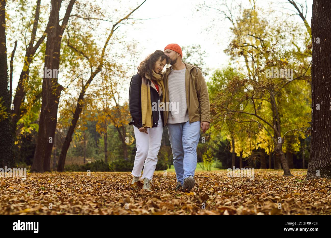 Couple affectueux se promenant dans un parc en automne, se câlinant parmi des couleurs chaudes et des feuilles Banque D'Images