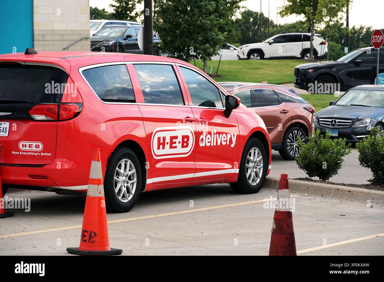 PLANO, TX, États-Unis - 6 JUILLET 2026 : Un camion de livraison rouge H-E-B est garé à côté de cônes de signalisation sur un parking. H-E-B est un supermarché américain populaire c Banque D'Images