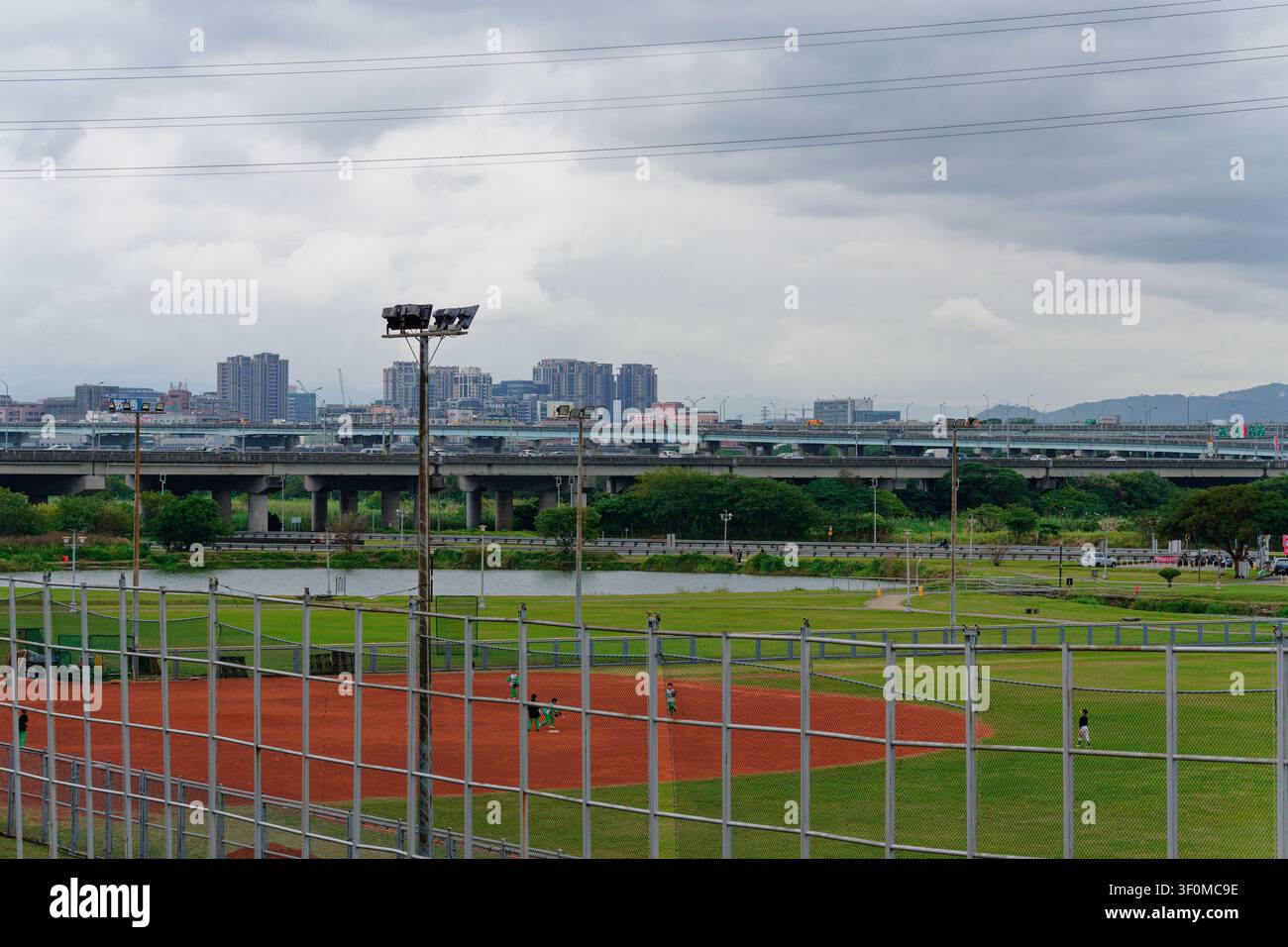 Nouvelle-Taïpeh, Taïwan - 20 janv. 2026 : Des élèves pratiquent le baseball sur un terrain riverain Banque D'Images