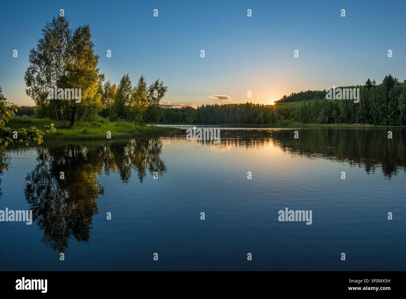 Un lac forestier tranquille en Russie centrale capture un coucher de soleil d'été éclatant. Banque D'Images