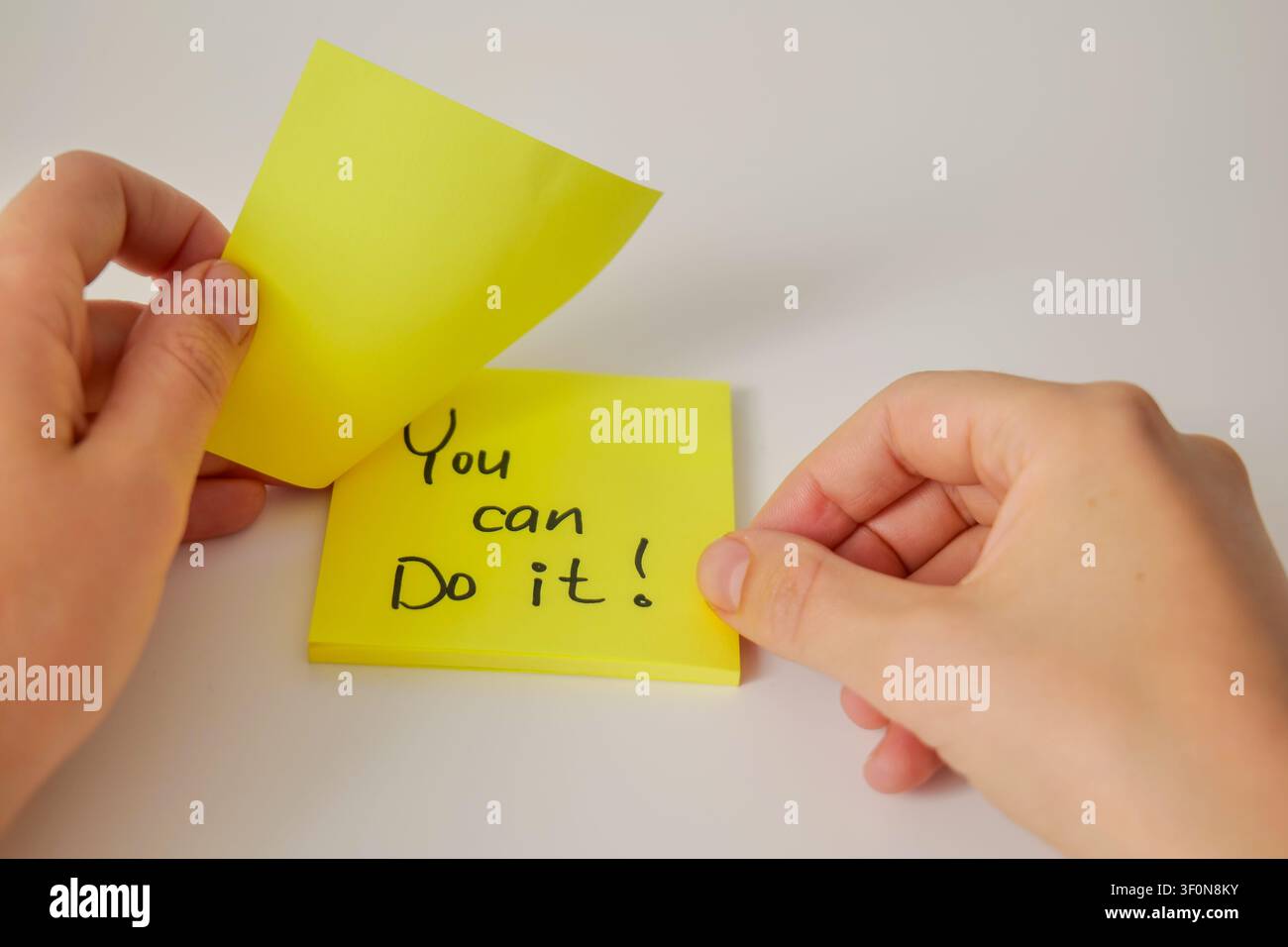 Main révélant un message "Tu peux le faire" sur une note collante Banque D'Images