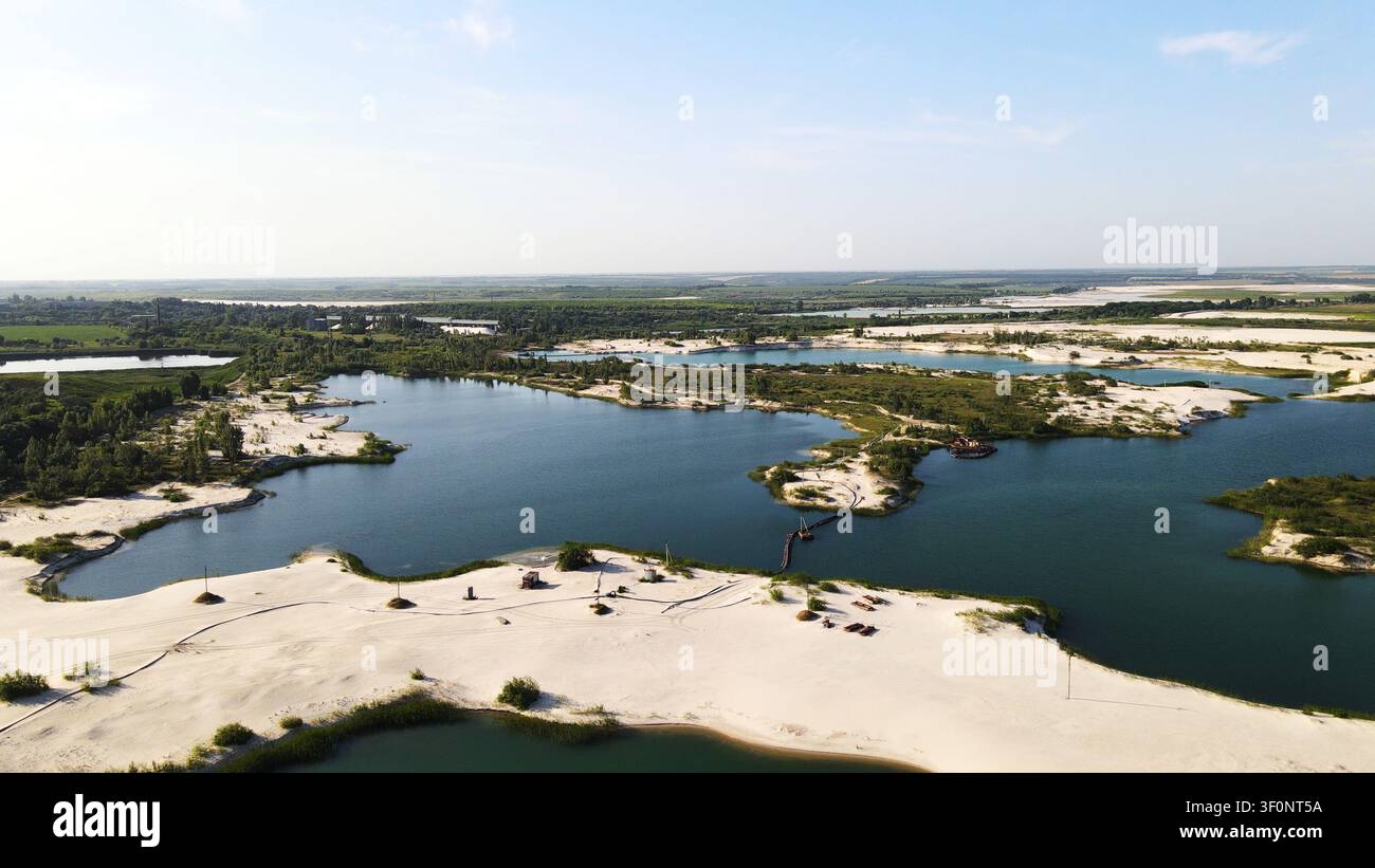 Vue aérienne d'une carrière de sable avec plusieurs lacs bleus et des rives de sable blanc, montrant l'extraction industrielle de l'eau Banque D'Images