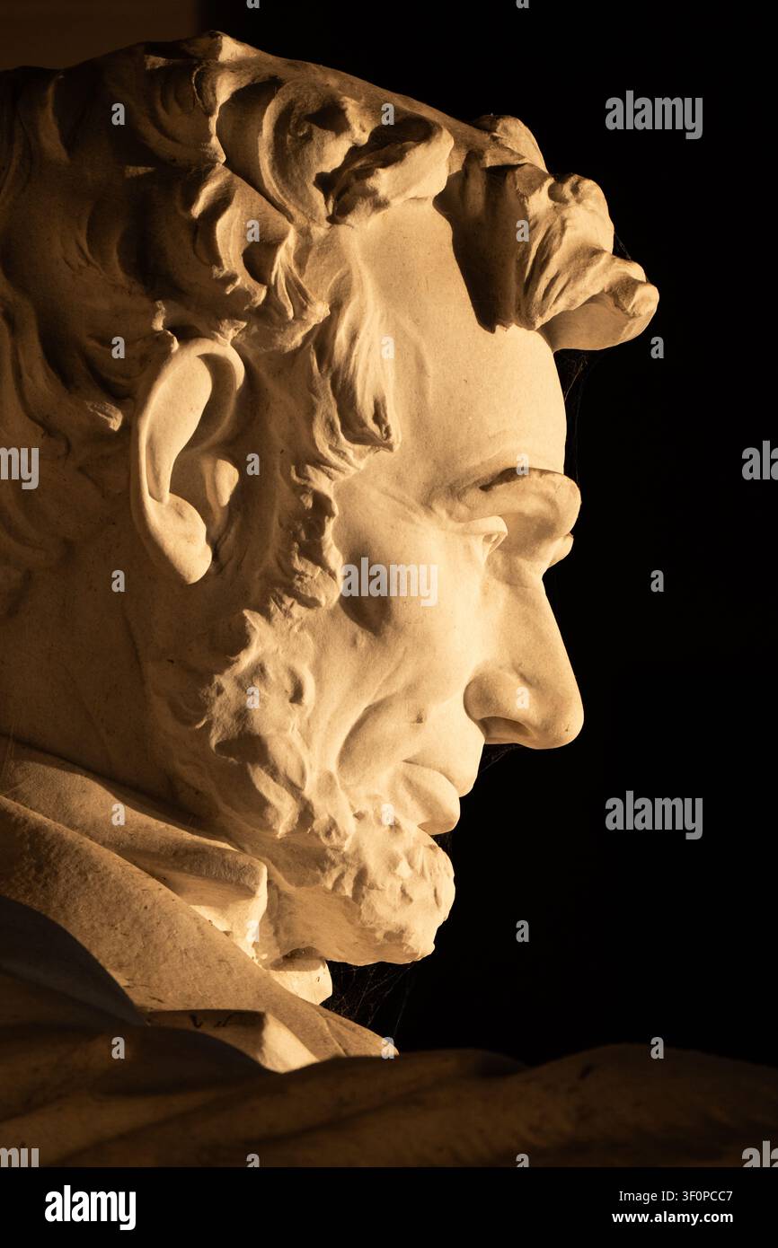 Profil de la statue de Lincoln à Washington DC | WASHINGTON D.C., États-Unis — La lumière de l’équinoxe oblique isole le profil du Lincoln de Daniel Chester French, taillé dans vingt-huit blocs de marbre de Géorgie ajustés avec des joints si précis qu’ils sont presque invisibles. Les frères Piccirilli ont découpé chaque bloc séparément dans leur atelier du Bronx et n’ont pas ajusté les pièces avant leur assemblage au mémorial en 1920. Banque D'Images