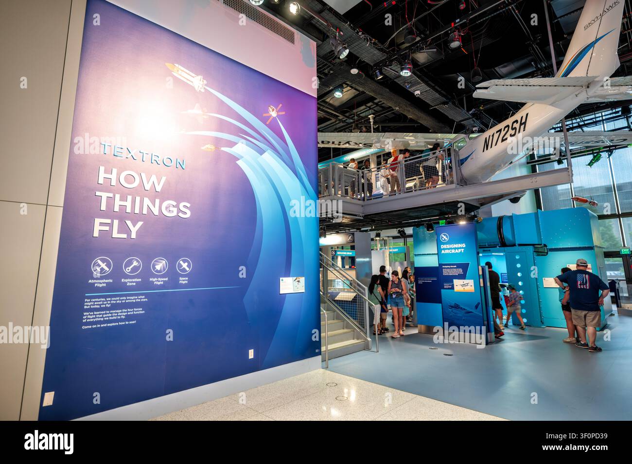 Galerie How Things Fly du Musée de l’air et de l’espace de Washington DC | WASHINGTON D.C., États-Unis — Les visiteurs se déplacent dans la galerie « Textron How Things Fly » du National Air and Space Museum, où une Cessna Skyhawk est suspendue au-dessus des stations interactives. L’avion d’entraînement monomoteur, immatriculé N172SH, a été construit par Textron Aviation en tant qu’objet pédagogique, permettant aux visiteurs de s’asseoir à l’intérieur tandis que des expositions voisines démontrent les quatre forces du vol : portance, poids, traînée et poussée. Banque D'Images