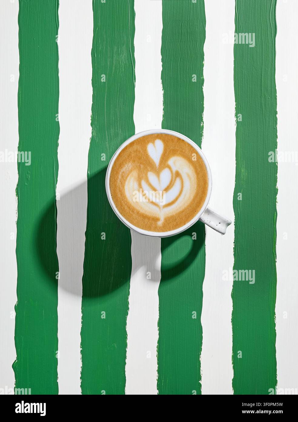 tasse à cappuccino en céramique blanche sur une table rayée vert et blanc peinte, vue de dessus Banque D'Images