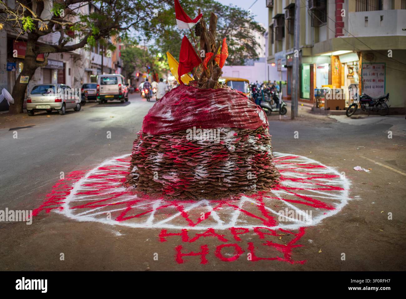 Un grand tas conique de bois et de galettes de bouse de vache séchées se trouve au milieu d'une rue à Jamnagar. La structure est décorée de poudres colorées, fl Banque D'Images