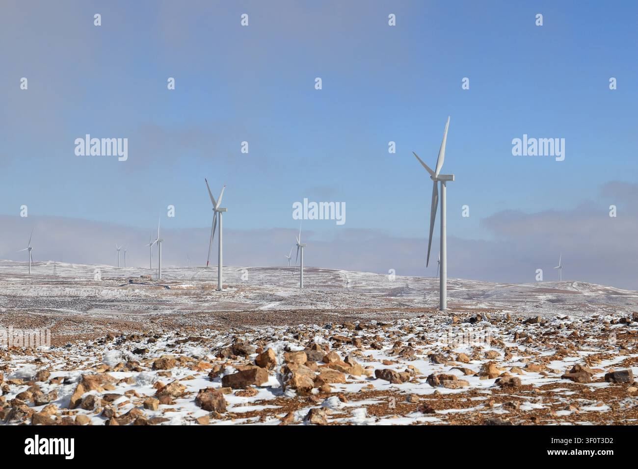 Vue de turbines éoliennes dans un paysage rocheux et enneigé, Al-Qadisiya, gouvernorat de Tafilah, Jordanie. Banque D'Images
