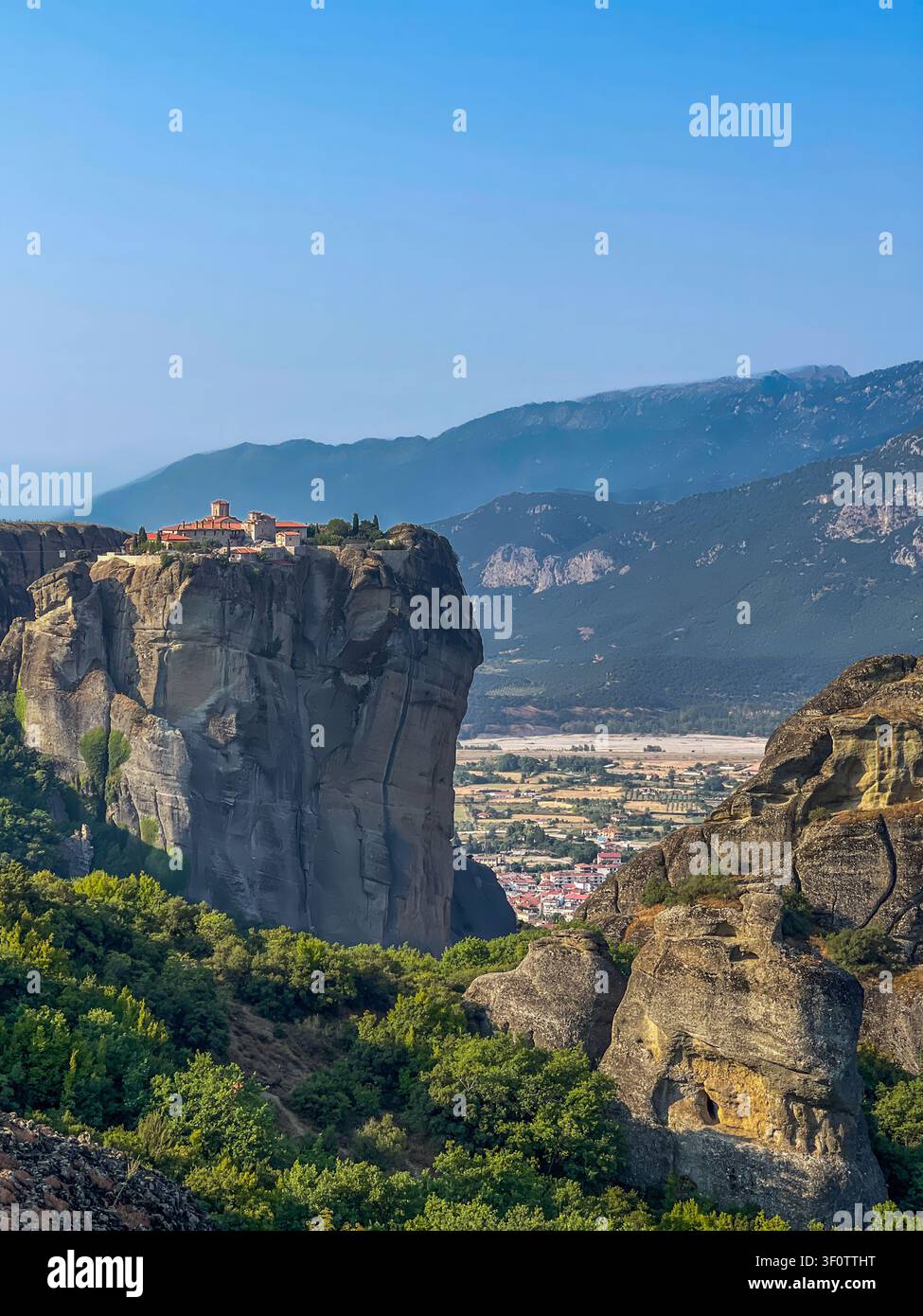 Kalambaka, Grèce – 24 juillet 2024 : groupe de monastères de Meteora. Monastère de la Sainte-Trinité sur son plateau rocheux, avec, bien en contrebas, la ville de Kalambaka Banque D'Images